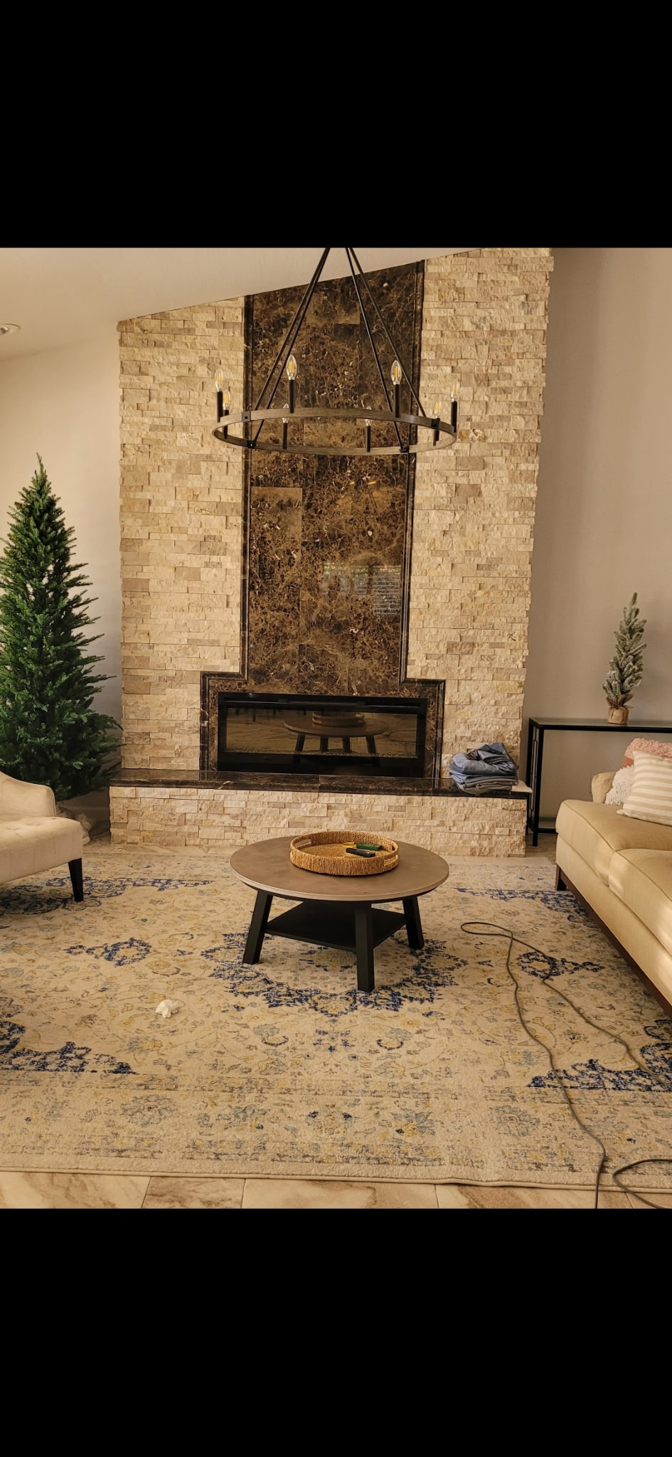 Furnished living room with finished stone fireplace surround and chandelier